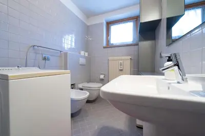 a white bathroom with a sink and a toilet at Cesa Azola in Vigo di Fassa