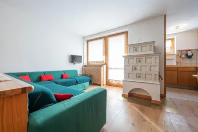 a living room with a green couch and a fireplace at Cesa Azola in Vigo di Fassa