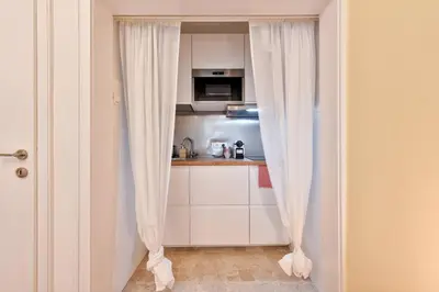a kitchen with white cabinets and white curtains at Lauben Studio Bolzano in Bolzano