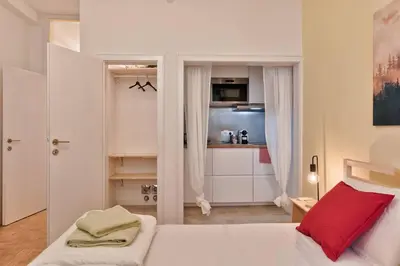 a bedroom with a white bed and a kitchen at Lauben Studio Bolzano in Bolzano