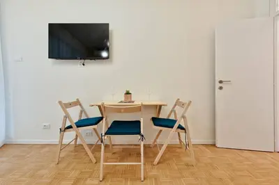a table and four chairs with a television on a wall at Lauben Studio Bolzano in Bolzano