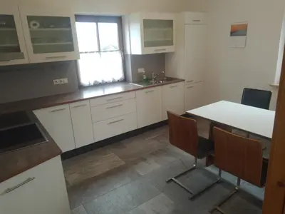 a kitchen with white cabinets and a table and chairs at Zirbentraum in Lana