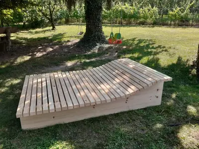 a wooden bench sitting in the grass next to a tree at Zirbentraum in Lana