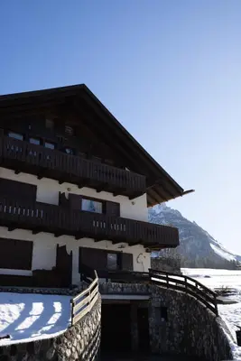 a building with snow on the ground in front of it at Casa Allegra, con balcone panoramico in San Vito di Cadore