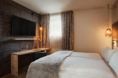 a hotel room with a bed and a desk at Hotel Tofana Cortina in Cortina dʼAmpezzo