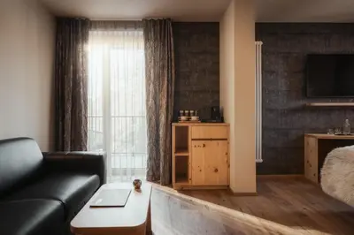 a living room with a couch and a bed and a television at Hotel Tofana Cortina in Cortina dʼAmpezzo