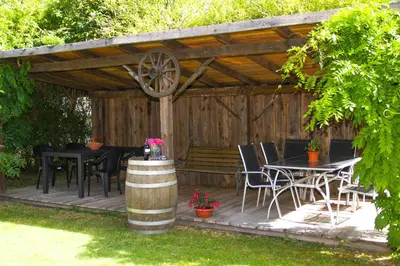a wooden deck with a table and chairs and a bench at Pension Astoria in Naturno