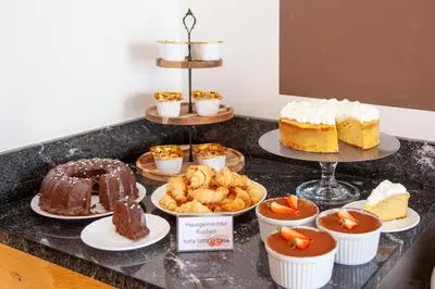 a counter topped with different types of cakes and desserts at Pension Astoria in Naturno