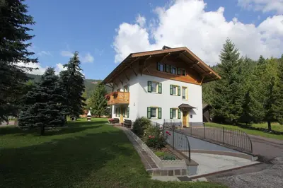 a large white house with a wooden roof at Appartamenti Ciasa Molin in Soraga