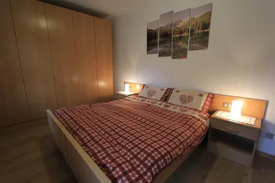 a small bedroom with a bed and two night stands at Appartamenti Ciasa Molin in Soraga