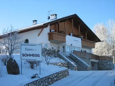 a house with a sign in front of it in the snow at Garni Sonnegg in Petersberg