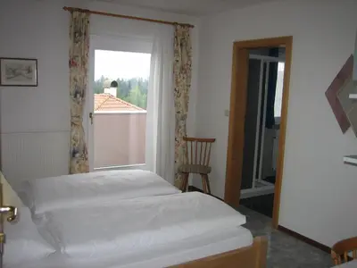 a bedroom with a bed and a window and a chair at Garni Sonnegg in Petersberg