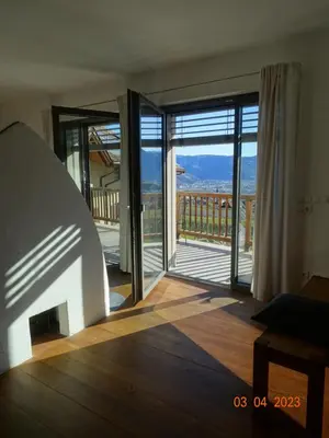 a room with doors open to a balcony with a view at Panoramaterrace, Wein & relax in Appiano Sulla Strada Del Vino