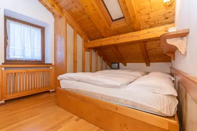 a bed in a room with a wooden ceiling at mansarda Lungolago in Alleghe