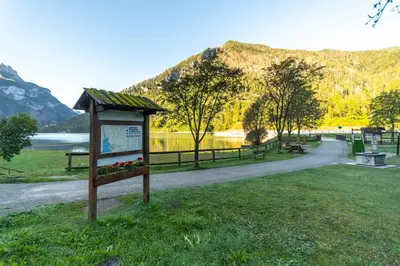 a sign in a park with a lake and mountains at mansarda Lungolago in Alleghe