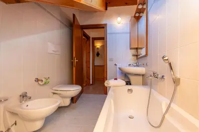 a bathroom with two toilets and a tub and a sink at mansarda Lungolago in Alleghe
