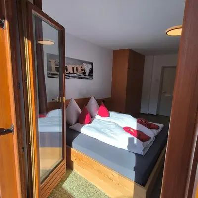 a bedroom with a bed with red pillows and a mirror at B&B Garni Lantschner in Kastelruth