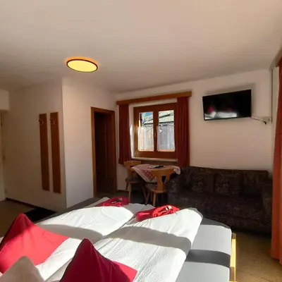 a hotel room with two beds and a couch at B&B Garni Lantschner in Kastelruth