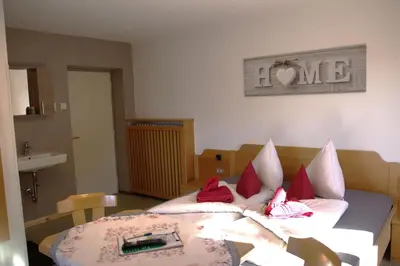 a room with a table and a couch with pillows at B&B Garni Lantschner in Kastelruth