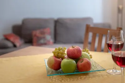 a plate of apples and grapes on a table with wine glasses at Ferienhof Hanna in Termeno