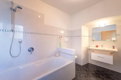 a white bathroom with a tub and a sink at Ferienhof Hanna in Termeno