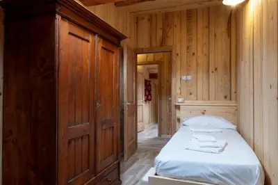 a bedroom with a bed and a wooden wall at ALLE ANTICHE MINIERE - CASA VACANZE in Zenich