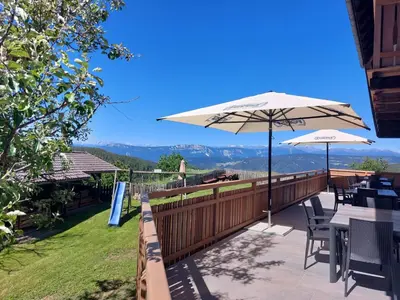 a patio with tables and umbrellas on a balcony at Webergütl in Auna di Sopra