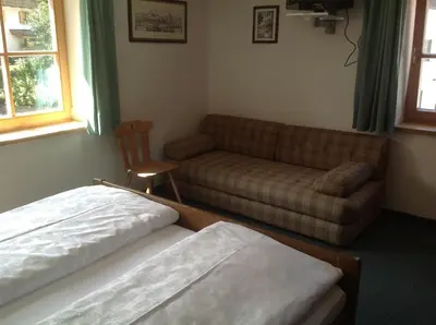 a living room with a bed and a couch at Garni Pineta in San Martino in Badia