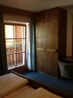 a bedroom with a bed and a window and a chair at Garni Pineta in San Martino in Badia