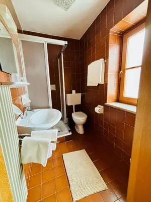 a bathroom with a tub and a toilet and a sink at Garni Pineta in San Martino in Badia
