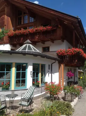 a building with chairs and flowers in front of it at Garni Pineta in San Martino in Badia