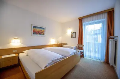 a bedroom with a large bed and a large window at Alara Rooms in Ortisei
