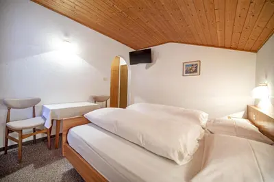 a hotel room with two beds and a table at Alara Rooms in Ortisei
