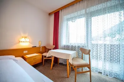 a hotel room with a bed and a table and a window at Alara Rooms in Ortisei