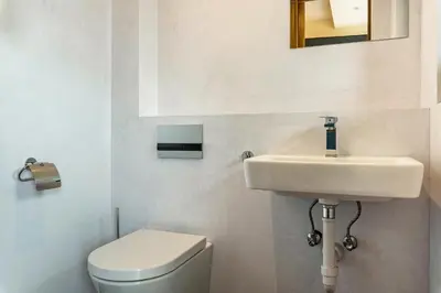 a white bathroom with a toilet and a sink at Villa Lara Föhre in Kastelruth