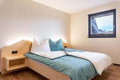 a bedroom with a wooden bed with a window at Villa Lara Föhre in Kastelruth