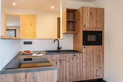 a kitchen with wooden cabinets and a sink at Villa Lara Föhre in Kastelruth