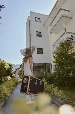a woman holding a suitcase and an umbrella at Alpimena Natur-Apartments Meran in Merano