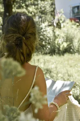 a woman sitting in the grass looking at her cell phone at Alpimena Natur-Apartments Meran in Merano