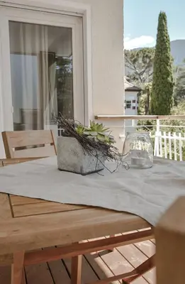 a table with a table cloth on top of a balcony at Alpimena Natur-Apartments Meran in Merano