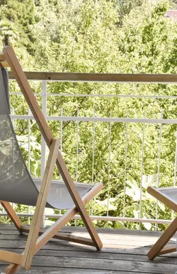 a rocking chair on a porch with a view of trees at Alpimena Natur-Apartments Meran in Merano