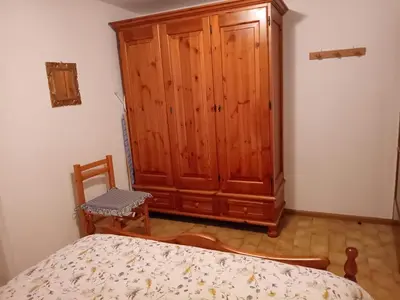 a bedroom with a wooden cabinet and a bed at Casa Sartorin in Canale San Bovo