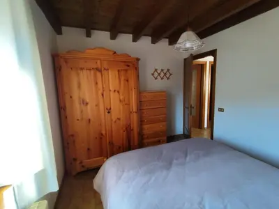 a bedroom with a bed and a wooden cabinet at Casa Relax in Canale San Bovo