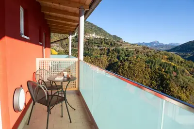 a balcony with a table and chairs and a view at Hostel L'Ost - Ostello di Grumes in Grumes