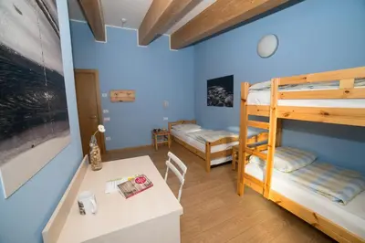 a room with two bunk beds and a table at Hostel L'Ost - Ostello di Grumes in Grumes