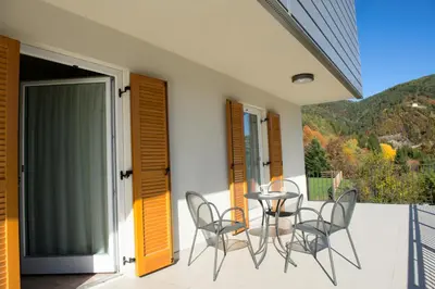 a patio with chairs and a table on a balcony at Hostel L'Ost - Ostello di Grumes in Grumes