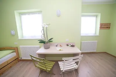 a room with a desk with two chairs and a bed at Hostel L'Ost - Ostello di Grumes in Grumes
