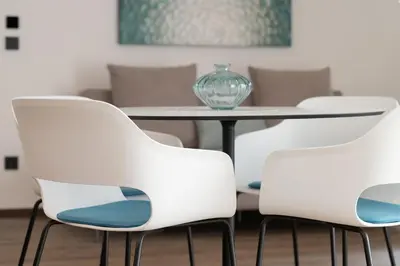 a table with white chairs and a glass vase on it at Moerlhof in Caldaro