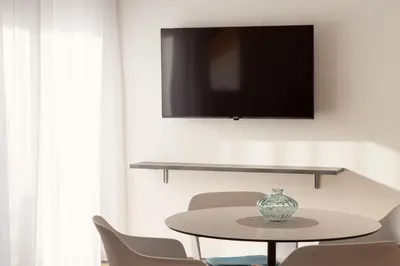 a table with chairs and a tv on a wall at Moerlhof in Caldaro