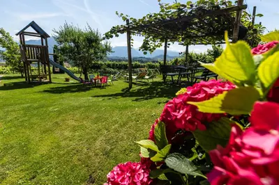 a park with a playground with tables and chairs and flowers at Weinhof Kager in Missiano